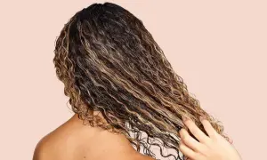 Cabello rizado y húmedo con reflejos dorados, mostrando cómo fortalecer el pelo con productos nutritivos.