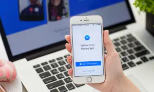 Jak włączyć dymki czatu w Messengerze na iPhone? Na ekranie telefonu widać ekran logowania do Messengera.