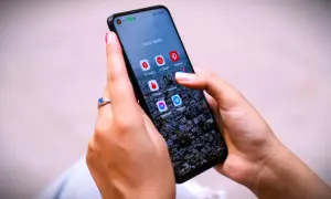 Dłoń z pierścionkiem na ekranie telefonu z ikonami aplikacji, w tym Messenger. Czy jak usunę wiadomość na Messengerze to on to widzi?