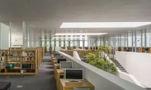 Nowoczesne wnętrze biblioteki Raczyńskich z rzędami regałów, komputerami i zielenią.