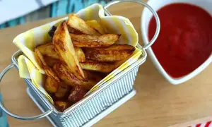 Un panier rempli de délicieuses frites au four dorées, à côté d'un bol de ketchup rouge vif.
