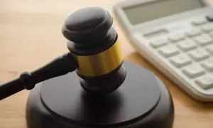 Młotek sędziowski i kalkulator symbolizują sprawiedliwość i finanse, być może w kontekście rozpatrywania wniosku o subwencję.