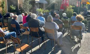 Un gruppo di persone ascolta un relatore durante un tricot cafè tutorial all'aperto.