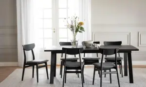 Ett modernt matbord med sex svarta stolar. Utrymme runt matbordet är inrett med en vas med blommor och en skål.