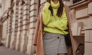 Modna stylizacja: neonowy sweter, płaszcz i spódnica w kratę.