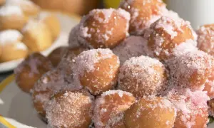 Castagnole marchigiane ricetta originale: dolcetti fritti dorati, cosparsi di zucchero semolato e un tocco di zucchero rosa.