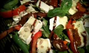 Sałatka z camembertem i suszonymi pomidorami, polana sosem balsamicznym, posypana pestkami słonecznika.