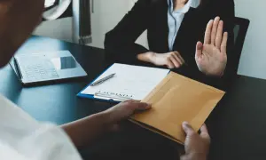 Une main tend une enveloppe, l'autre la refuse. Une scène évoquant le délai réponse inspection du travail licenciement salarié protégé.