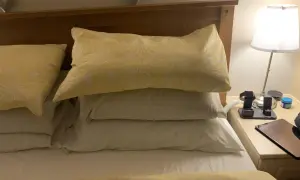 A stack of three pillows, one with a yellow sunflower pattern, sits on a bed. Perfect for sleeping with 3 pillows for ultimate comfort.