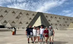 Rodzina pozuje przed nowoczesnym muzeum w Gizie, którego fasada ozdobiona jest geometrycznymi wzorami.