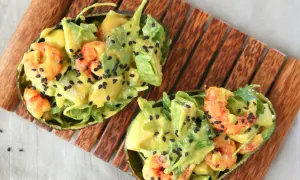 Deliciosa ensalada de langostinos y aguacate, servida en mitades de aguacate y espolvoreada con semillas de sésamo negro.