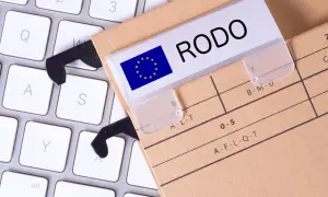Dokumentacja RODO na teczce z etykietą "RODO" i flagą UE, leżąca na klawiaturze. To rejestr czynności przetwarzania.