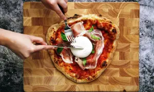 Une pizza burrata avec du prosciutto et du basilic, prête à être dégustée.