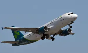 Samolot Aer Lingus z zieloną koniczynką na ogonie wznosi się na błękitne niebo.