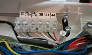 Zaciski elektryczne z numerowanymi wejściami i wiązką kolorowych przewodów.