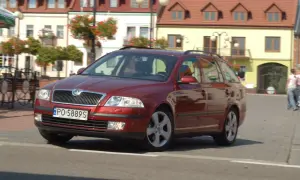 Czerwona Skoda Octavia 2 kombi na ulicy, z widocznymi żarówkami w przednich reflektorach.
