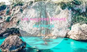 Aguas turquesas y acantilados verdes en las mejores playas de Nerja. Un kayak navega cerca de una cascada.