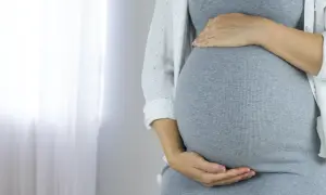 Kobieta w ciąży z dłońmi na brzuchu. Może to być związane z cholestazą ciążową.