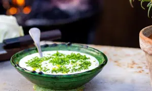 Grönskande skål med krämig ranch dressing, toppad med färska örter. En sked vilar i skålen, redo att servera.
