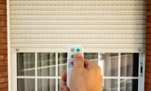 Mano che usa un telecomando per alzare una tapparella elettrica. Utile per capire quanto costa mettere le tapparelle elettriche.