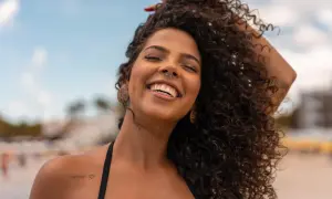Donna sorridente con capelli ricci e fluenti, un esempio di come trattare i capelli ricci per un look naturale e radioso.