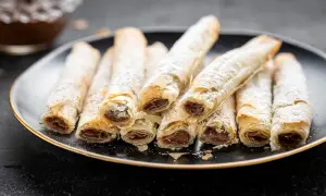 Rotolini croccanti di pasta fillo ripieni di cioccolato, spolverati di zucchero a velo.
