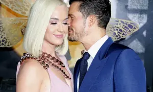 Orlando Bloom szepcze coś do ucha Katy Perry, która uśmiecha się z zamkniętymi oczami.