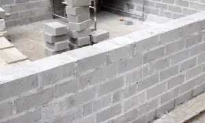 Budowa fundamentów z bloczków betonowych. Stos szarych bloczków betonowych fundamentowych czeka na użycie.