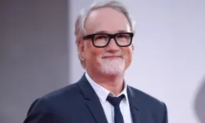 David Fincher, reżyser znany z mrocznych i wciągających filmów, w eleganckim garniturze i okularach.