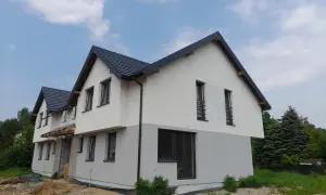 Nowy dom w stanie surowym, z szarym dachem i dwukolorową elewacją. Zastanawiasz się, ile trwa budowa domu 100m2?