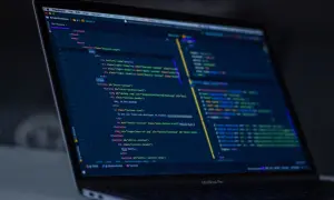 Code sur un écran d'ordinateur portable, affichant du code HTML et JavaScript, avec des éléments de développement web, comme un `EventEmitter` dans Angular.