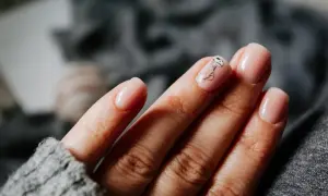 Une main aux ongles rose pâle, avec une délicate méduse dessinée sur l'annulaire. Une manucure pastel subtile et élégante.