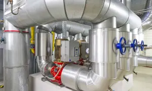 Detailaufnahme einer Anlage mit großen Rohren, Pumpen und Ventilen, die an ein mini blockheizkraftwerk angeschlossen sind.