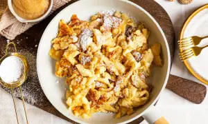 Kaiserschmarrn ohne Ei, fluffig und goldbraun, mit Puderzucker bestäubt. Dazu Apfelmus und zwei Gabeln.