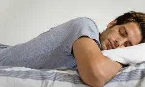 Hombre durmiendo boca abajo, con la cabeza apoyada en una almohada. Se pregunta: "porque sudo mucho cuando duermo soy hombre".