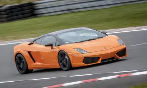 Pomarańczowe Lamborghini pędzi po torze wyścigowym, zostawiając za sobą smugę prędkości.
