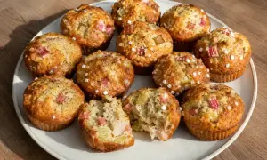 Fredriks rabarbermuffins, gyllene och toppade med pärlsocker, ser ljuvliga ut. En muffin är uppdelad och visar saftig rabarber.