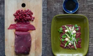 Förberedelser för asiatisk råbiff: rått kött i bitar och skivor på en skärbräda, färdig rätt med gurka, örter och sesamfrön på en grön tallrik.