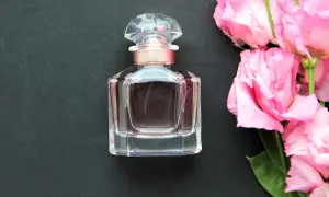 Elegancka buteleczka wody toaletowej obok bukietu różowych kwiatów. Wybór między wodą toaletową a wodą perfumowaną zależy od preferencji.