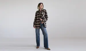 Kobieta w beżowo-czarnej koszuli w kratę i dżinsach, prezentująca styl country.
