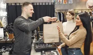Hombre entrega bolsas de compras a dos mujeres en una tienda.