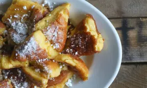Ein Teller mit goldbraunem, zerrupftem Kaiserschmarrn, bestäubt mit Puderzucker. Perfekt für ein gemütliches Kaiserschmarrn Rezept.