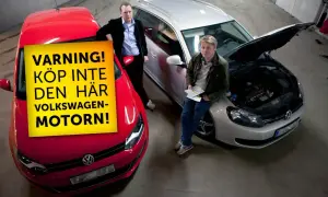Två män står vid en röd Volkswagen och en silverfärgad kombi med öppen motorhuv. En gul skylt på den röda bilen varnar för vanliga fel på Volkswagen-motorn.