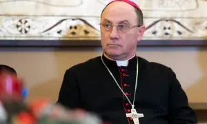 Prymas Polski w okularach i czarnej sutannie z krzyżem na łańcuszku.