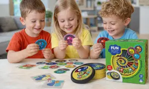Niños sonríen jugando "Camaleón", un juego de mesa con cartas de colores. Ideal para actividades para niños de 6 a 12 años, fomenta la atención y velocidad.