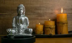 Srebrny Budda w medytacji, otoczony płonącymi świecami. Czy buddyści wierzą w reinkarnację? Ta scena sprzyja refleksji.