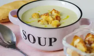 Kremowa zupa z selera naciowego z grzankami w różowej miseczce z napisem "SOUP".