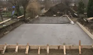 Plac budowy z wylana betonowa płyta fundamentowa i zbrojenie.