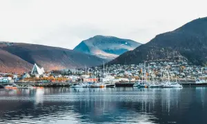 Tromsø im Sommer: Segelboote im Hafen vor einer Stadt am Berghang, gekrönt von der markanten Eismeerkathedrale.