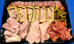 Plateau de charcuterie : terrines, jambon, saucisson, cornichons et tomates cerises. Idéal pour savoir que mettre dans un plateau de charcuterie.